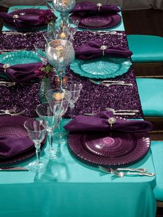 the table is set with purple and teal plates, silverware, and napkins