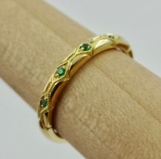 "This beautiful hand engraved and millgrain wedding band is 2.3 mm wide and 1.8 mm tall made of 18k yellow but we can make it in any 18k or 14k color of gold. The 7 tsavorite garnets are set approximately 2/3 way on top and have a total weight of .05 Cts. We can make it any size from 5-7 and you still be able to return it within the listed time frame. Sizing outside of that range can be made as a special order and may require a resize fee if returned. Ring sizing may add additional handling time Formal Yellow Gold Tsavorite Rings, Ceremonial Yellow Gold Emerald Heirloom Ring, Gold Tsavorite Emerald Ring For Formal Occasions, Formal Gold Emerald Ring With Tsavorite, Ceremonial Heirloom Yellow Gold Emerald Ring, Classic Tsavorite Emerald Ring For Wedding, 14k Yellow Gold Jewelry With Certificate Of Authenticity, Emerald Ring Stamped 14k As Gift, Gift Emerald Ring With 14k Stamp And Round Band