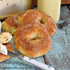 some sugared donuts are sitting on a table next to a glass of milk