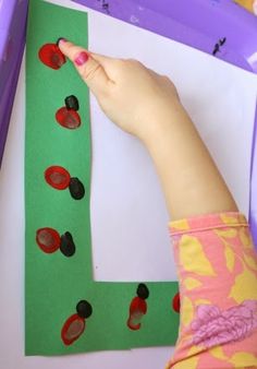 a child's hand is touching the letter l made out of paper and buttons