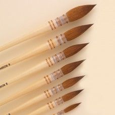 six wooden brushes lined up in a row