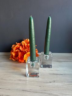 two green candles sitting next to each other on a table