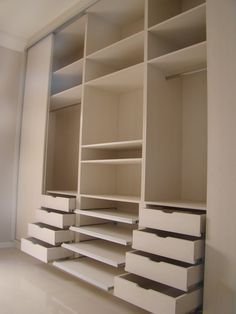 an empty white closet with drawers and shelves