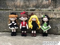 four crocheted dolls are lined up against a stone wall