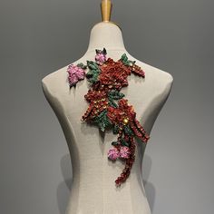 a white mannequin with red and pink flowers on it's back neck