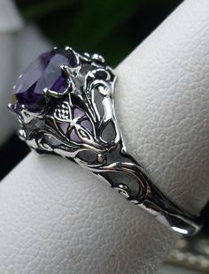 Natural Amethyst Ring Daisy Design#66 In Stock Size 6 Inspired by the Art Nouveau movement of the early 20th century, I now offer this lovely reproduction filigree ring in sterling silver. This gorgeous ring is set with a genuine/natural 1.5ct purple amethyst gemstone; which has a great shine and very good clarity. The round full cut purple amethyst gemstone is 8mm (5/16th of an inch) in diameter. The ring measures 12mm NS on the finger. The inside of the band is marked 925 for sterling. Notice Purple Anniversary Rings With Intricate Design, Purple Gemstone Filigree Ring For Wedding, Purple Amethyst Rings With Intricate Design, Purple Oval Ring With Intricate Design, Oval Purple Ring With Intricate Design, Oval Amethyst Ring With Intricate Design, Wedding Purple Filigree Ring With Gemstone, Purple Intricate Design Promise Ring, Purple Promise Ring With Intricate Design