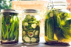 three jars filled with pickles and cucumbers