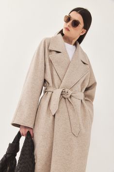 A heavy weight longline rode coat. An oversize fit with long voluminous sleeves and side pockets. Features a lapel collar with an embroidered logo. Comes with a detachable waist belt. A cozy worm coat you can wear over any outfit. 100% Polyester Color: Beige Care: Dry clean only Oversize fit, take your usual size. Model wears: M Model's fit:1.75 cm Waist 59 cm Hips 86 cm Bust 78 cm How to measure yourself Voluminous Sleeves, How To Measure Yourself, Model Fits, Grey And Beige, Sweaters Knitwear, Lapel Collar, Waist Belt, Skirt Pants, Heavy Weight