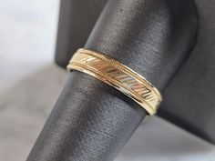 a close up of a gold ring on a black cloth with a white and gray background