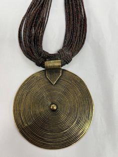 A beautiful handmade brass pendant from Ghana hangs on a hand weaved leather. The necklace is a collectible art and would be perfect for adding to your African jewelry collection or a major statement piece to wear. Black African Necklace, Traditional Handwoven Gold Jewelry, Handmade Metal Medallion Necklace For Festivals, Brown Necklace With Adjustable Cord For Festivals, Adjustable Bronze Copper Necklace, Artisan Brown Handwoven Necklace, Bohemian Bronze Jewelry With Brass Buttons, Handmade Bohemian Medallion Necklace, Bohemian Brown Necklace With Large Pendant