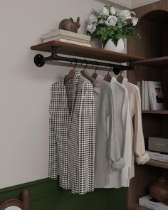 a shelf with clothes hanging on it and a potted plant in the corner next to it