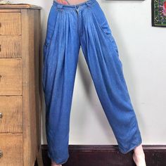 "Vintage Pleated Denim Trousers by Reserve, Styled by Biscote.  1980s High Waisted Jeans with Pleats, Baggy Thigh, and Tapered Ankle, Size Small.  These soft jeans are absolutely amazing!  Super high rise pants are made of a soft viscose that is between a chambray and a denim.  Tons of small pleats at the front of the waist help to create a baggy hip and thigh with massive fashion pockets down the sides.  The legs taper toward the ankle, and the seat of the pants is smooth and fitted.  Absolutel Retro Baggy Full-length Bottoms, Retro Full-length Baggy Bottoms, Baggy Vintage Denim Blue Pants, Vintage Baggy Denim Blue Pants, Retro Full Length Baggy Bottoms, Retro High-waisted Jeans For Summer, Retro High-waisted Summer Jeans, Retro Dark Wash Pants For Spring, Vintage Baggy Denim Pants