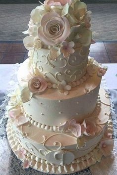 a three tiered wedding cake with pink flowers on the top and white icing