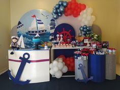 a birthday party with balloons and decorations on the wall, including an anchor cake stand