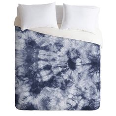 a blue and white comforter set with two pillows on top of the bed in front of it