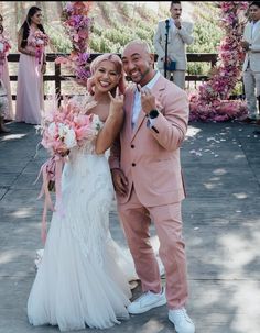 a man and woman standing next to each other in front of an arch with flowers