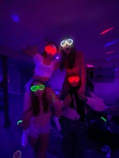 three girls wearing neon goggles in a dark room