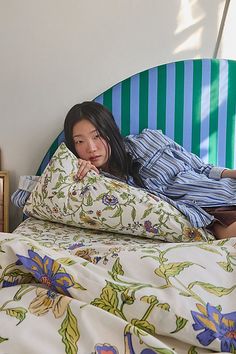 a woman laying on top of a bed next to a blue and green headboard