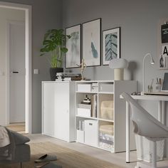 a living room with white furniture and pictures on the wall above it's desk