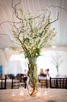 a vase filled with white flowers on top of a table next to two votive candles