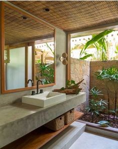 a bathroom with two sinks and plants in the window sill, along with an outdoor shower