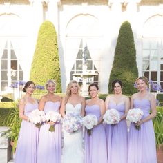 a group of women standing next to each other in front of a building with flowers