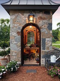 an open door to a stone building with potted plants