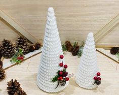 two white plastic christmas trees with pine cones and berries on the top, sitting next to each other