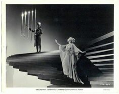 an old black and white photo of a woman standing on stairs next to a man