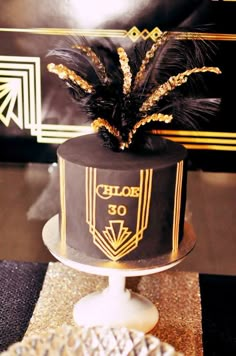 a black and gold cake with feathers on top