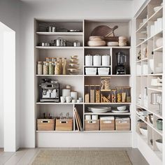 an organized pantry with white shelves and baskets