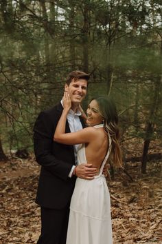 a man and woman standing next to each other in the woods