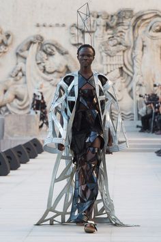 a model walks down the runway wearing an unusual outfit made out of metal strips and wire