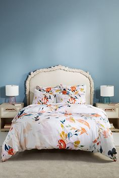 a bed with a white headboard and pillows on it in a blue walled room