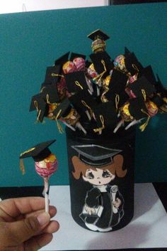 a person holding a lollipop with graduation decorations in it