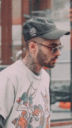 a man with tattoos wearing sunglasses and a hat