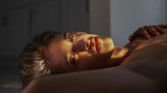 a man laying on top of a bed next to a white wall in a room