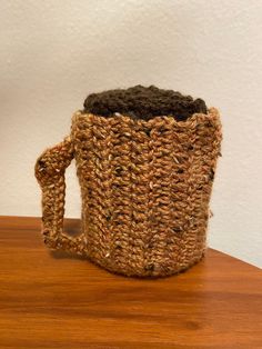 a crocheted coffee cup holder sitting on top of a wooden table