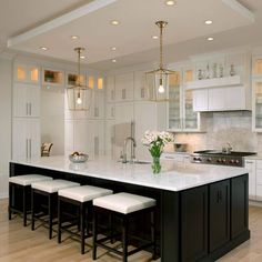 a large kitchen with white cabinets and marble counter tops, an island with four stools