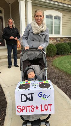 a woman standing next to a baby in a stroller with a sign on it