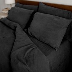 a bed with black sheets and pillows on it