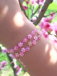 a close up of a person's arm wearing pink bracelets with flowers on them