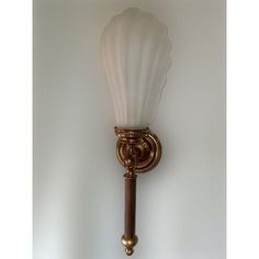 a wall light with a white glass shade on it's arm and an antique brass finish