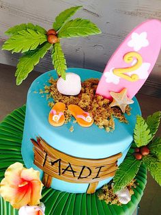 a surfboard cake on top of a green leafy plate with flowers and leaves