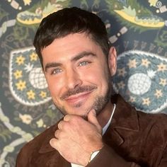 a close up of a person with a watch on his wrist and a wallpaper behind him