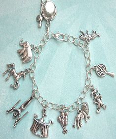 This charm bracelet features circus/carnival inspired tibetan silver charms. The charms are attached to a silver tone chain bracelet that measures 7.5 inches in length. SKU 1148 Symbolic Charm Bracelet With Dangling Charms, Whimsical Silver Dangling Charms, Symbolic Metal Charm Bracelet With Dangling Charms, Silver Novelty Charm Bracelet, Silver Novelty Bracelets With Charms, Novelty Silver Metal Charm Bracelet, Silver Novelty Metal Charm Bracelet, Novelty Silver Hypoallergenic Charm Bracelet, Whimsical Silver Charm Bracelet