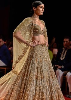 Molten gold heavily embroidered lehenga paired with crystal encrusted blouse and cape veil across shoulder glamourized with a feather tulle trail. Lehenga Cape, Cape Veil, Rahul Khanna, Molten Gold, Cape Set, Embroidered Lehenga, Nehru Jackets, Western Wedding, Wedding Service