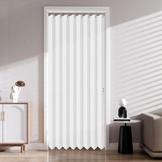 a living room with white walls and flooring next to a sliding door that has vertical blinds on it