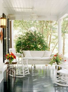 a porch with rocking chairs and flowers on it