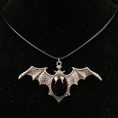 Please read descriptions thoroughly for sizes and materials. A special jewelry adhesive is use to attach pieces to bails where noted.  This is a large eye catching silver metal pendant featuring a silver bat type shape, with its wings spread, and a large black resin cabochon. It is hung from a black faux leather woven waxed cord that is 19 1/2" long, with silver chain and a silver lobster claw clasp. * Also available on a 18" 20"or 30" silver stainless steel snake chain.  Make sure to check out my shop for more hair pins, jewelry, accessories, and all sorts of fun stuff! Bat Necklace, Goth Necklace, Gothic Necklace, Wing Necklace, Bat Wing, Silver Black Bat, Vampire Jewelry, Bat Jewelry, Vampire Necklace Jewelry Vampire, Vampire Necklace, Vampire Jewelry, Bat Jewelry, Bat Necklace, Resin Cabochon, Goth Necklace, Necklace Gothic, Gothic Accessories